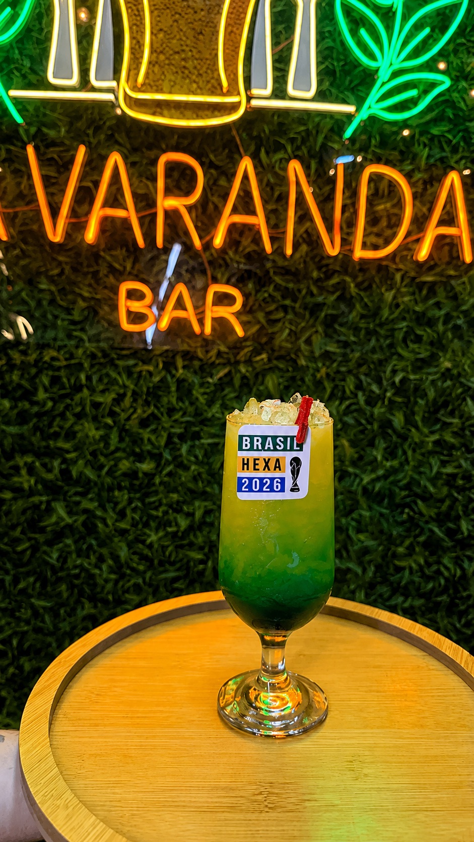 Drink colorido à frente da placa iluminada do Varanda Bar